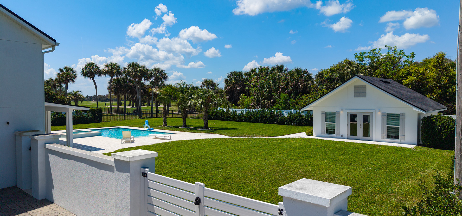 Rear exterior of a Ponte Vedra home with lawn and pool area
